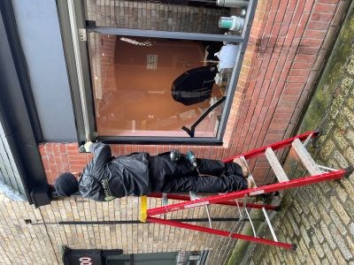 man on laddter servicing steel window shutters